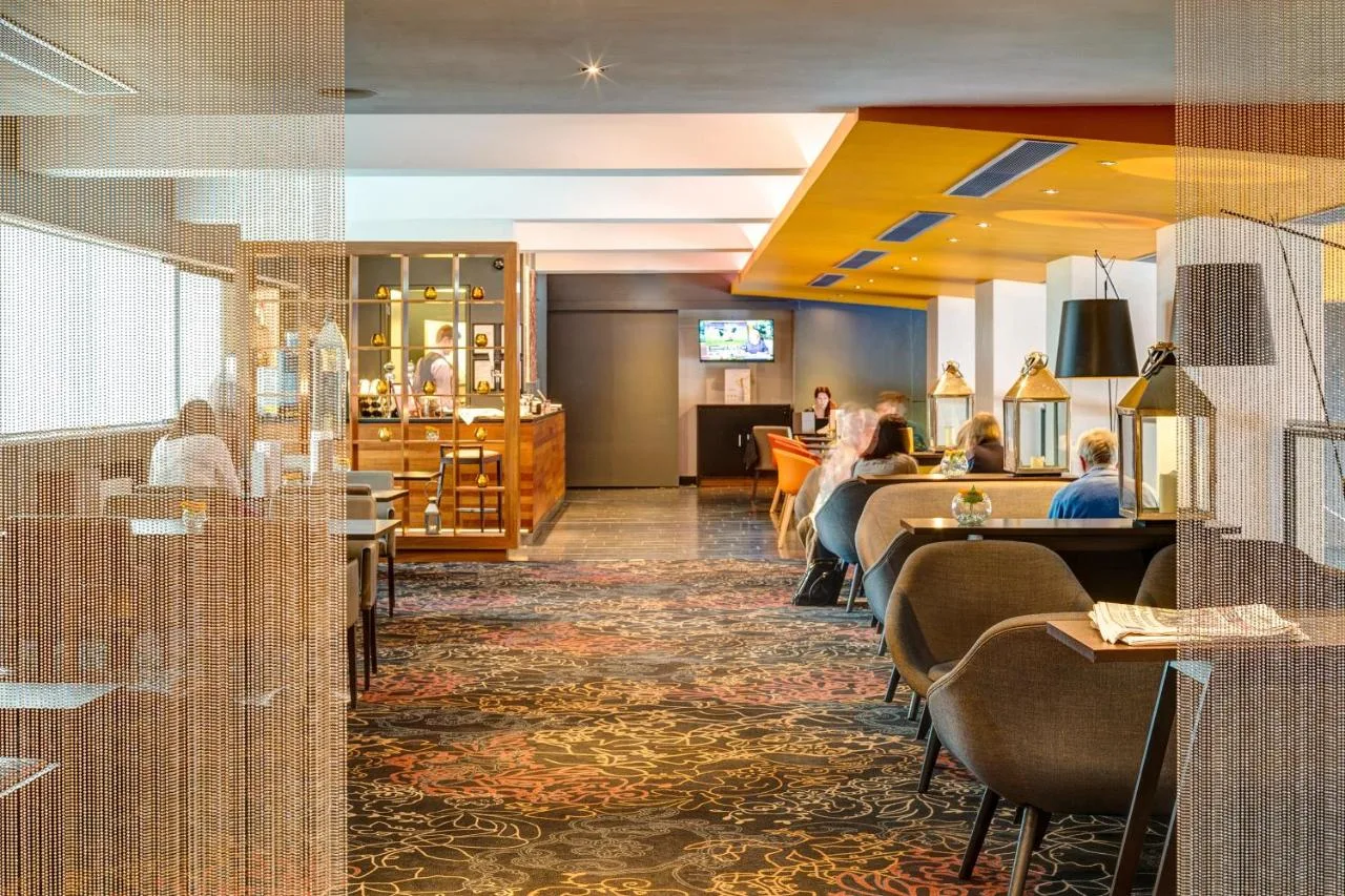 a lobby of a hotel with people sitting at tables at Apex Grassmarket Hotel in Edinburgh