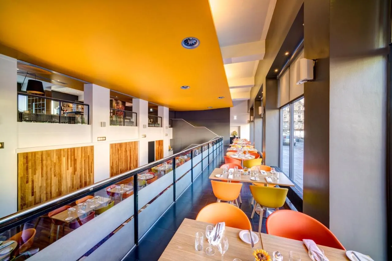 a restaurant with long tables and orange chairs at Apex Grassmarket Hotel in Edinburgh
